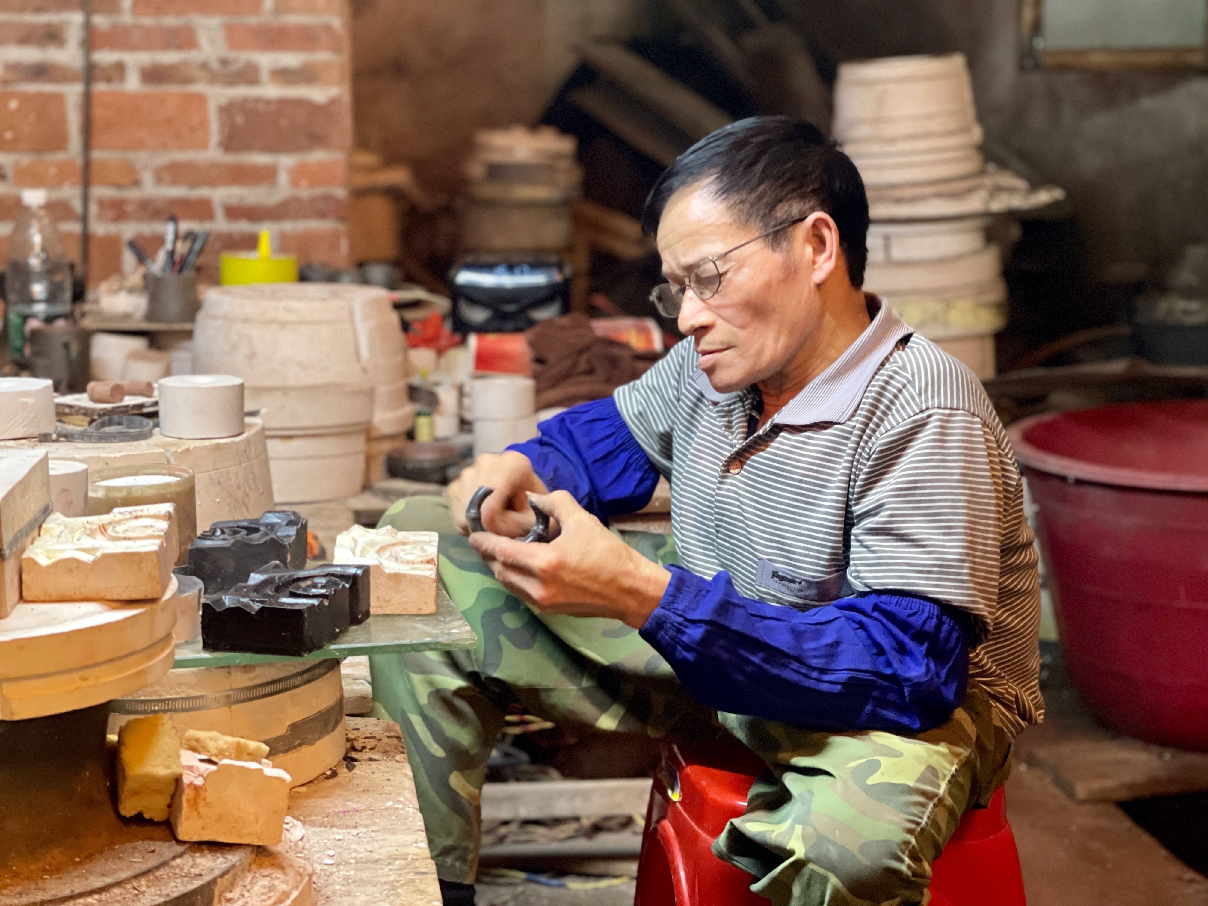 在广西钦州，“二哥”卢德成在坭兴陶生产车间制作模具。人民网 周静圆摄
